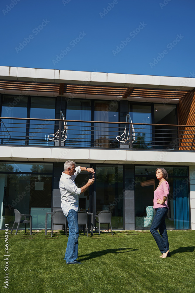 Obraz premium Elderly man photographing woman in house yard