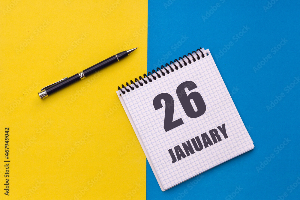 January 26th. Day 26 of month. Calendar date. Notebook with a spiral and pen lies on a yellow-blue background January 26th. Day 26 of month. Calendar date. Notebook with a spiral and pen lies on a yellow-blue background