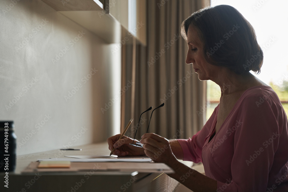 Aged lady sitting at desk and writing on paper Aged lady sitting at desk and writing on paper
