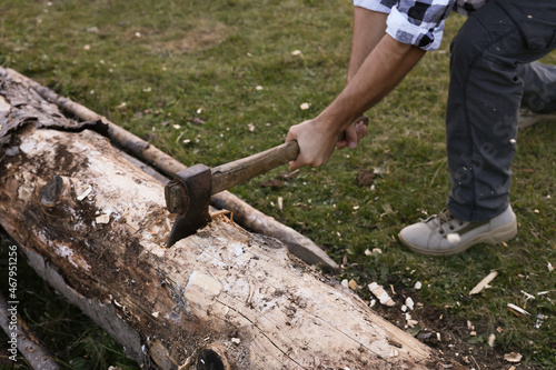 Man with axe cutting wood outdoors, closeup