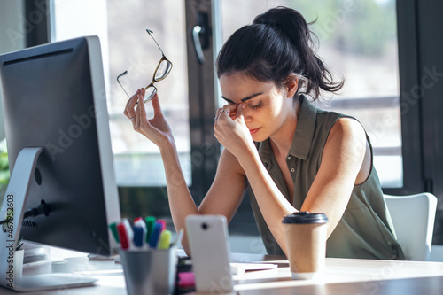 Tired business woman with headache looking uncomfortable while working with computer in the office