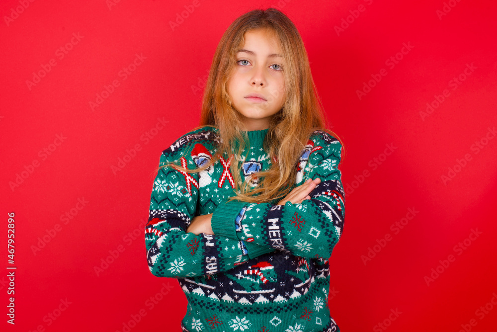 Picture of angry brunette kid girl in knitted sweater christmas over red background looking camera. Picture of angry brunette kid girl in knitted sweater christmas over red background looking camera.