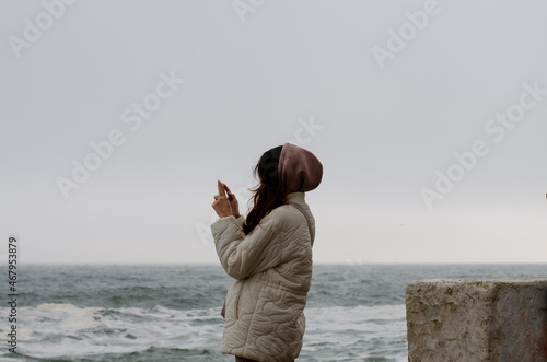 Girl by the sea. A lonely girl takes pictures. Rest by the sea. Stormy ocean.