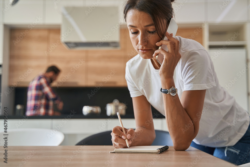 Beautiful Caucasian woman in casual clothes having dialogues on a mobile phone at home Beautiful Caucasian woman in casual clothes having dialogues on a mobile phone at home