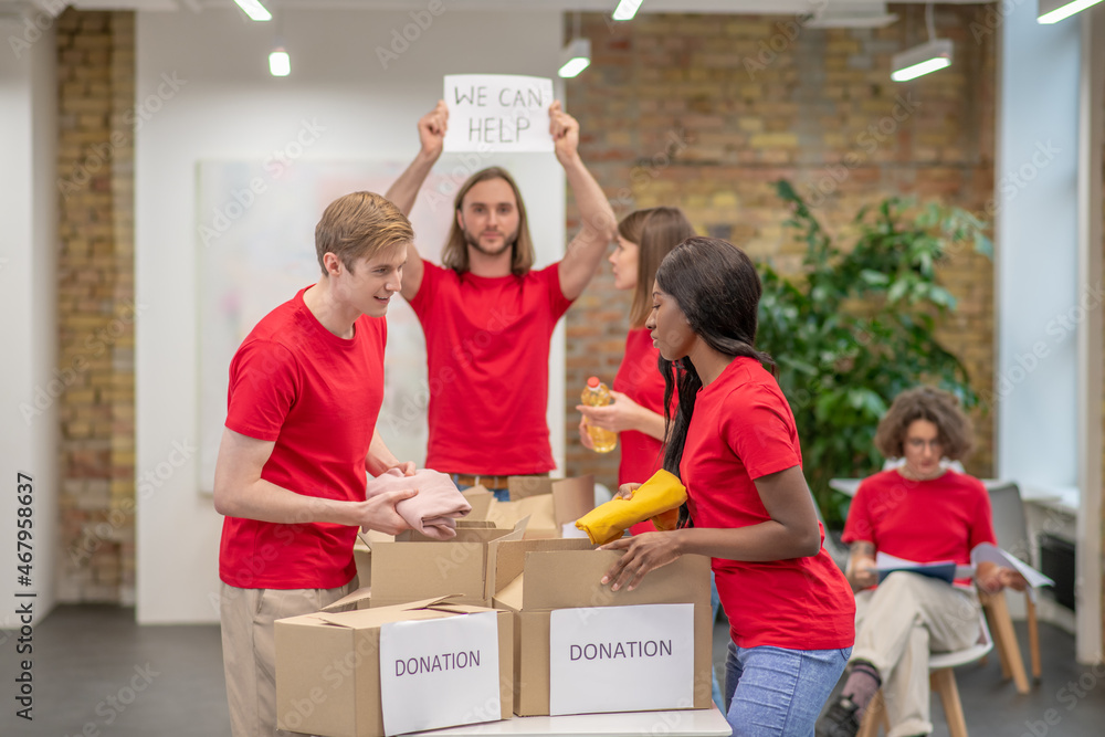 Young volunteers in red tshirts distributing donations in a sorting center Young volunteers in red tshirts distributing donations in a sorting center
