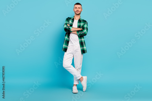 Full body photo of charming happy young man hold hands crossed good mood enjoy isolated on blue color background