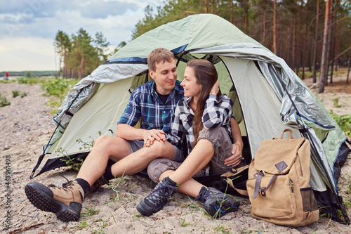 Romantic couple camping outdoors and sitting in a tent.