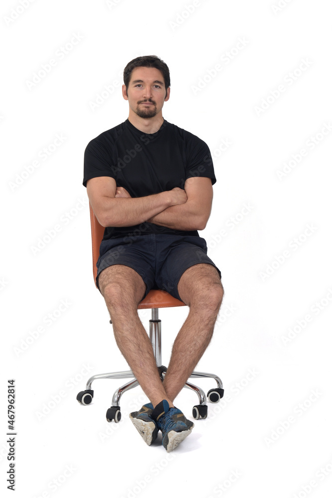 front view of a full portrait of a man sitting on a chair, arms crossed, wearing sportswear on white background front view of a full portrait of a man sitting on a chair, arms crossed, wearing sportswear on white background