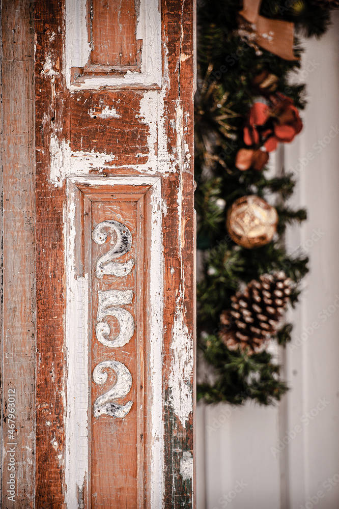 Old, weathered, textured wooden door frame with address and christmas wreath in background