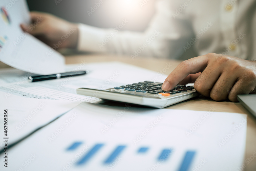 Close up hand of professional accountant review tax paperwork and signing signature on the table in workplace Close up hand of professional accountant review tax paperwork and signing signature on the table in workplace
