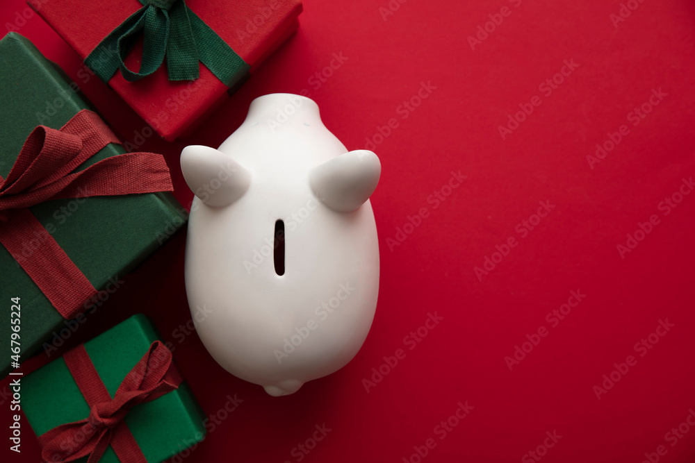 Festive Christmas financial savings concept. White piggy bank money box with presents Festive Christmas financial savings concept. White piggy bank money box with presents