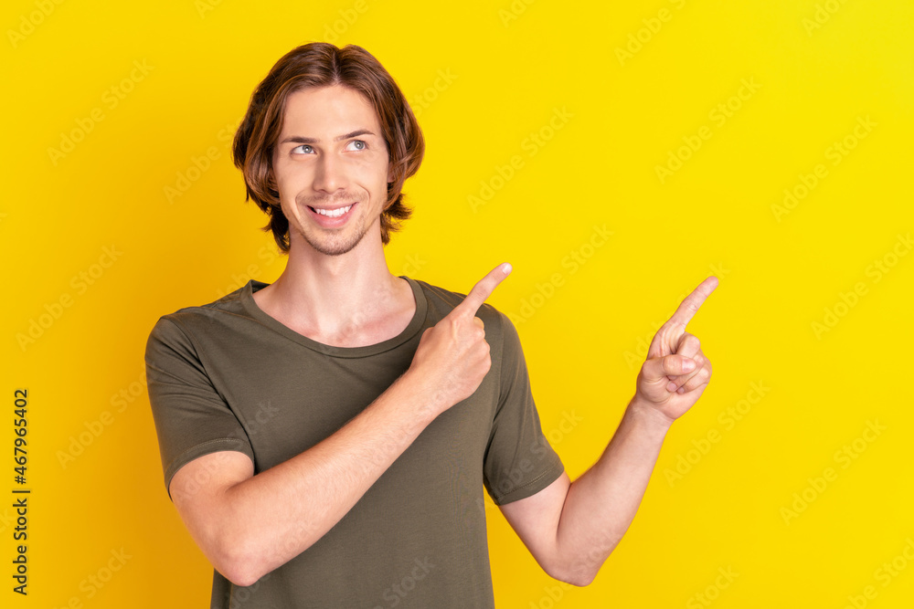 Photo of young cheerful man interested look indicate fingers empty space sale promo advertise isolated over yellow color background Photo of young cheerful man interested look indicate fingers empty space sale promo advertise isolated over yellow color background