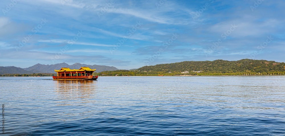 Tranquility and beautiful scenery at West Lake in Hangzhou, China, as Chinese style tour boat floats across the water Tranquility and beautiful scenery at West Lake in Hangzhou, China, as Chinese style tour boat floats across the water