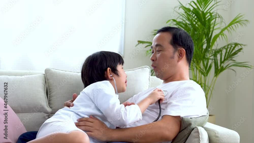 Asian father and son playing doctor and patient The son uses a stethoscope to listen to his father's heartbeat. Asian father and son playing doctor and patient The son uses a stethoscope to listen to his father's heartbeat.