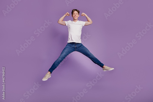 Full body photo of young man jump up show hands muscles bodycare sportive isolated on violet color background