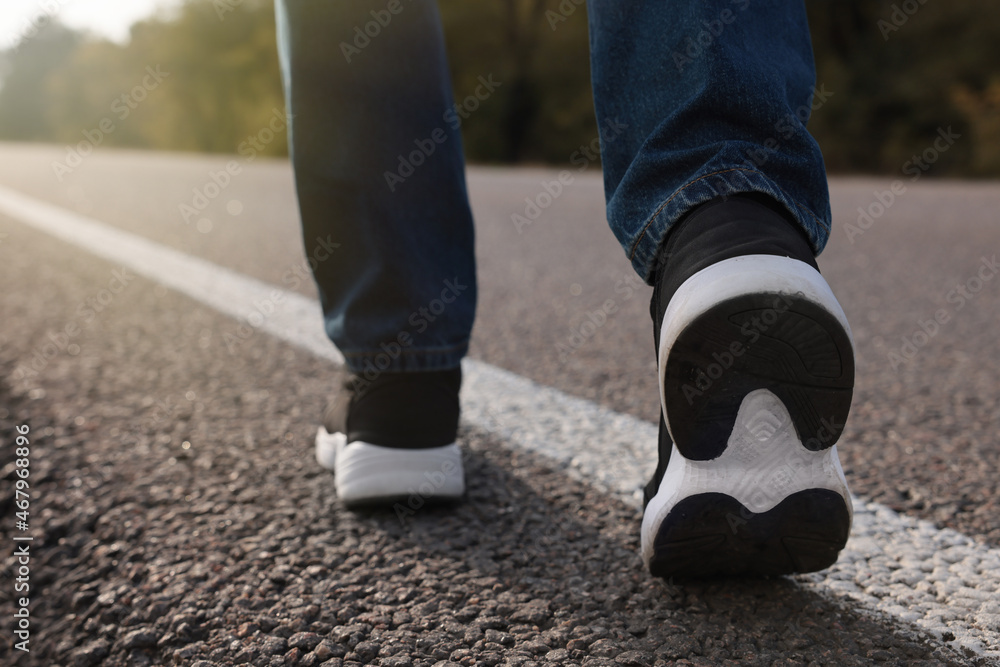 Man going along road, closeup of legs