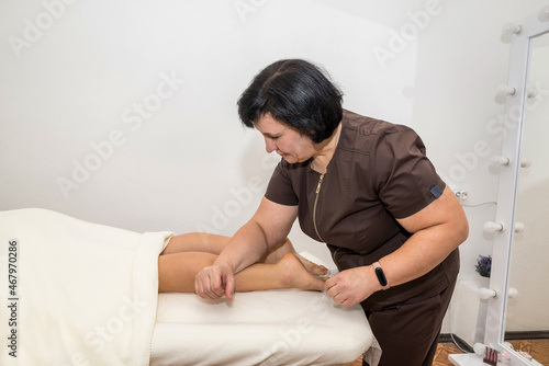 A woman masseuse makes a foot massage to a girl client in a massage parlor