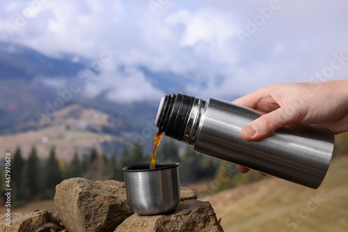 Woman pouring hot instant coffee from thermos in mountains, closeup