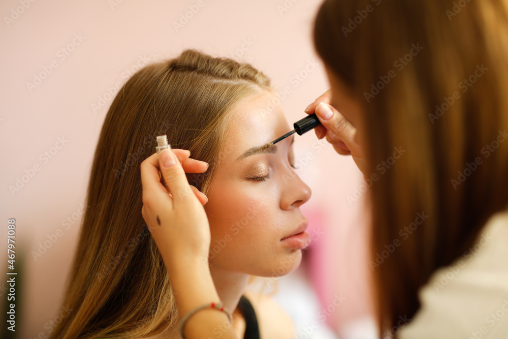 Fototapeta premium Makeup artist paints the bride before the wedding. Girl makeup artist paints a beautiful young woman with long hair, care and beauty, Two modern female friends having conversation and applying.
