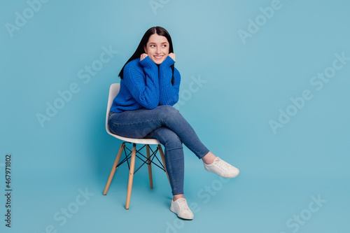 Full length profile side photo of young cheerful girl happy positive smile sit chair dream look empty space isolated over blue color background