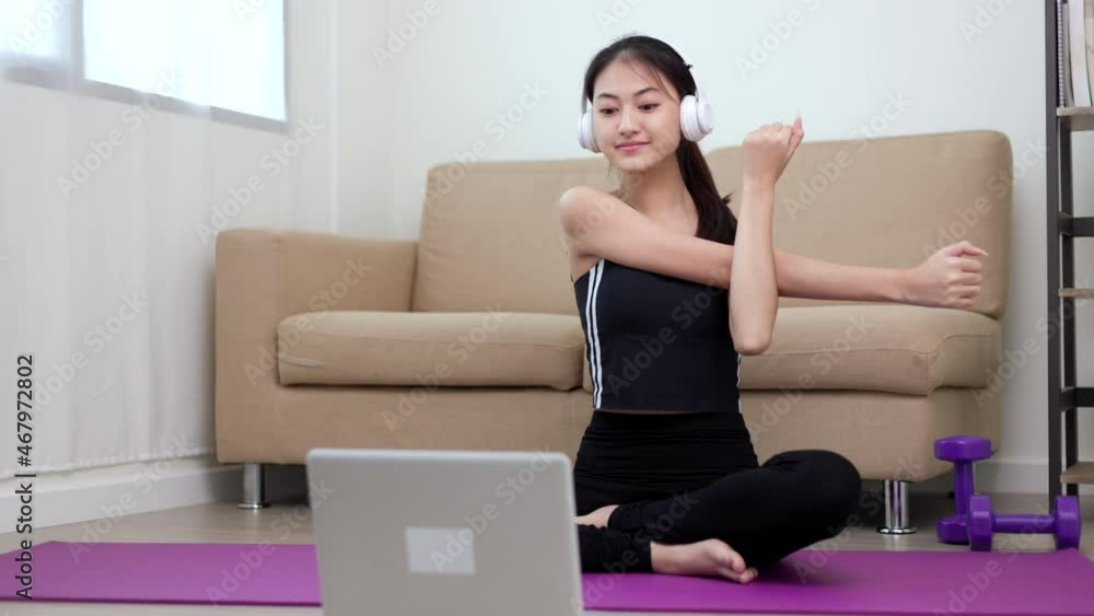 Beautiful asian woman in sportswear put on headphone learning exercise lesson on laptop by teaching online. Stay at home and practicing fitness class lose weight social distancing by video conference Beautiful asian woman in sportswear put on headphone learning exercise lesson on laptop by teaching online. Stay at home and practicing fitness class lose weight social distancing by video conference