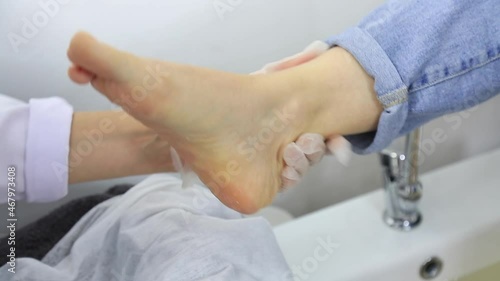 Young woman getting professional pedicure in beauty salon - handheld shooting 