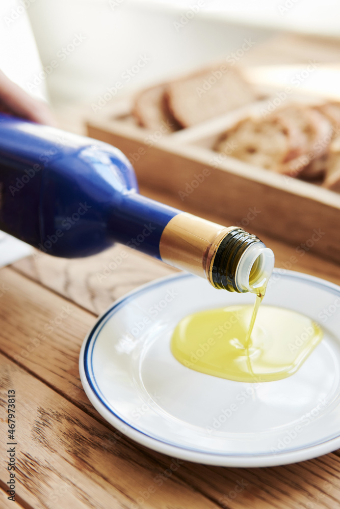 Olive Oil Pouring into a Saucer Close Up with Bread - obrazy, fototapety, plakaty 
