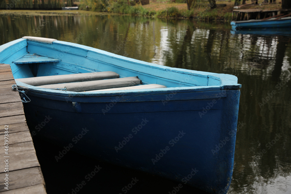 Light blue wooden boat on lake near pier, closeup