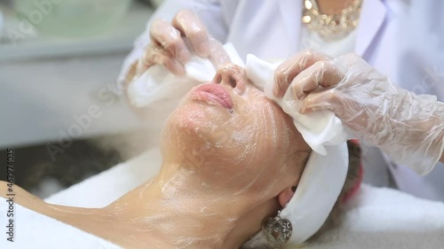 Facial peeling mask, spa beauty treatment, skin care. Woman getting facial treatment by beauty at spa salon, side view close up. Beautiful woman getting face massage in beauty spa. handheld shooting 