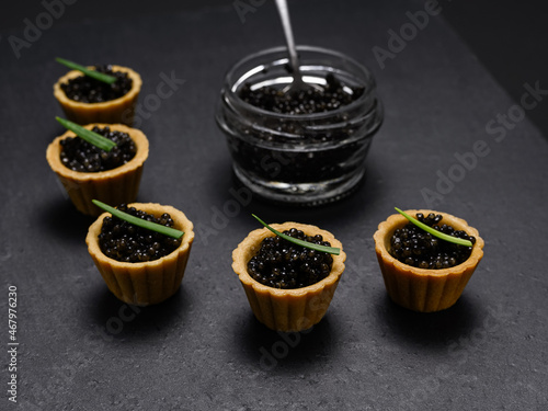 a delicacy of Russian cuisine - tartlets with natural black sturgeon caviar on a slate plate