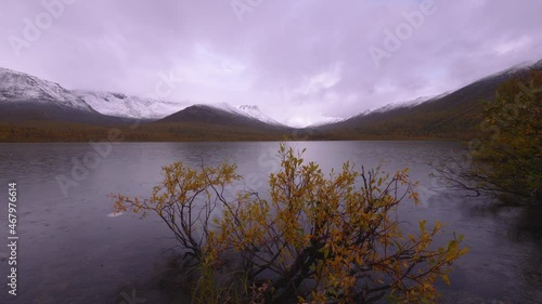 beautiful view of a mountain lake in the rain. Mountain snow-capped peaks in the background. Autumn in the Khibiny mountains.