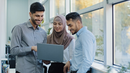 Multiethnic colleagues listens Arabic team leader explain corporate task application to diverse workers indian businesspeople looking on laptop screen working together, teamwork brainstorm concept