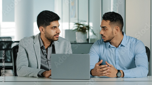 Confident arabic male financial consultant adviser expert talking to indian client customer explain commercial investment deal benefit show computer presentation at bank loan negotiation meeting