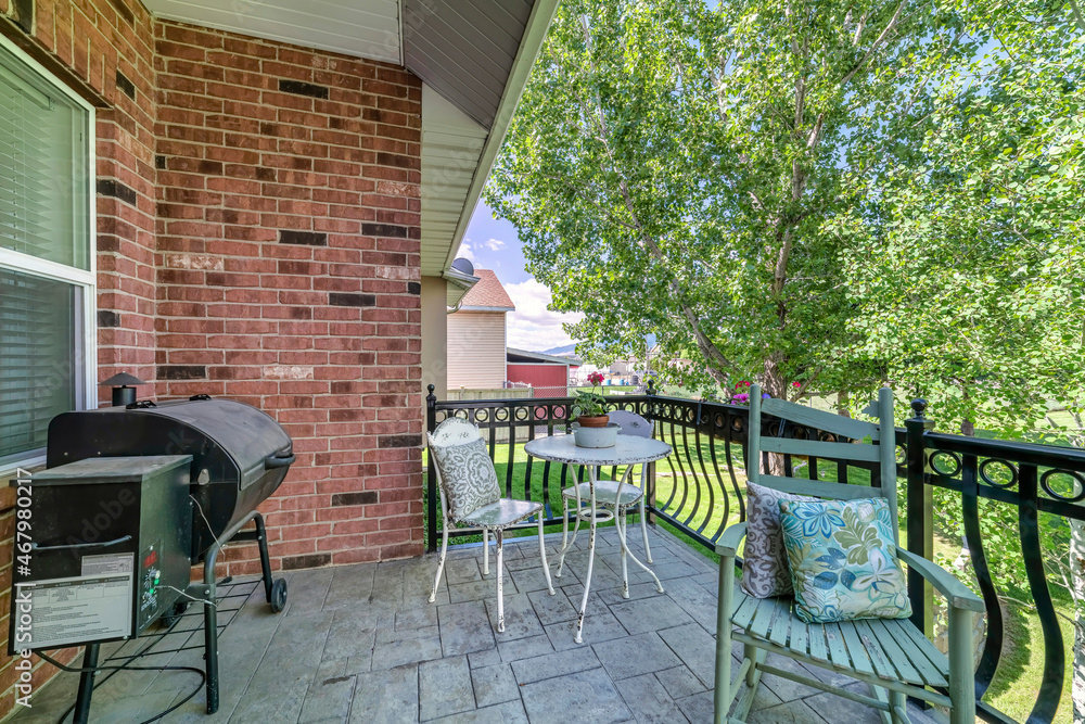 Deck of a house with barbecue grill, chairs and a view of the yard and neighborhood Deck of a house with barbecue grill, chairs and a view of the yard and neighborhood