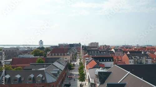 Forward slow flight through Torvegade street in Esbjerg, Denmark, with pedestrians strolling downtown. Aerial dolly revealing Esbjerg harbor in background photo