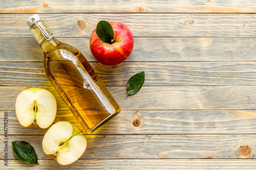 Photo Bottle of organic apple cider vinegar with red apples