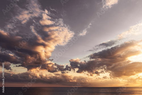 pink and gold clouds in the sky over the sea during sunset © Andrew