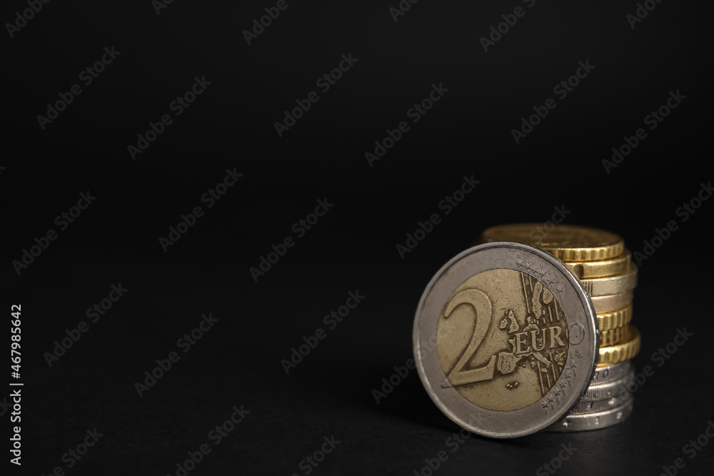 Many Euro coins stacked on black background, closeup. Space for text Many Euro coins stacked on black background, closeup. Space for text