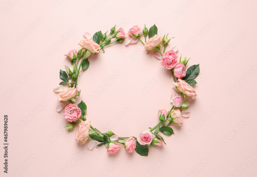 Wreath made of beautiful flowers and green leaves on pale pink background, flat lay. Space for text