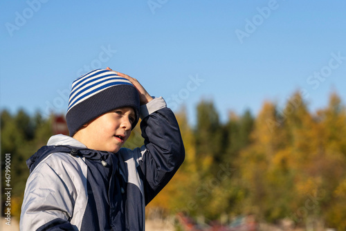 Portrait of a cute Caucasian boy 5 years old in a knitted striped hat on a walk on an autumn sunny day