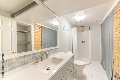Interior of a bathroom with corner shower stall near the gray shower curtain
