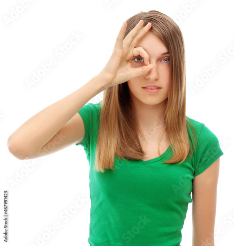 Portrait of young girl looking through OK sign