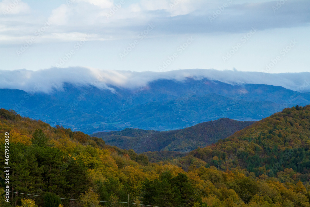 Paesaggio collinare con le cime delle montagne piene di nuvole in autunno