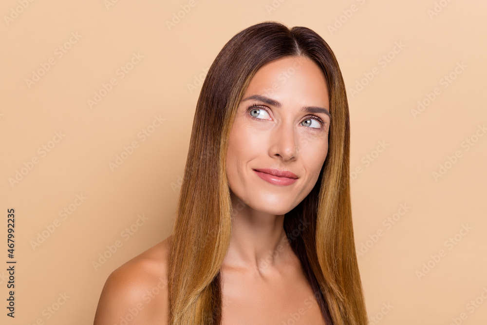 Fototapeta premium Portrait of attractive minded dreamy woman with flawless smooth skin thinking choosing cosmetic isolated over beige pastel color background