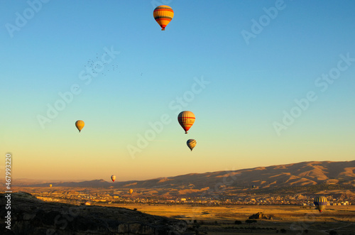 Goreme, Turkey-October 9,2021:Air balloons festival in Cappadocia. Few hot air balloons against colorful vibrant sky. Picturesque nature landscape in the background © evgenij84