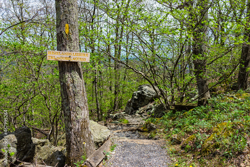 Sunny weather at Wintergreen ski resort village town with steps stairs on nature Highlands leisure hiking trail in forest of Virginia in spring with sign for hike access