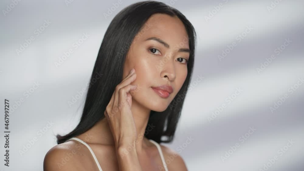 Female Beauty Portrait. Beautiful Diverse Asian Brunette Woman Posing, Smiling, Touching Her Face with Natural, Healthy Skin. Wellness and Skincare Concept on Soft Isolated Background. Close Up. Female Beauty Portrait. Beautiful Diverse Asian Brunette Woman Posing, Smiling, Touching Her Face with Natural, Healthy Skin. Wellness and Skincare Concept on Soft Isolated Background. Close Up.