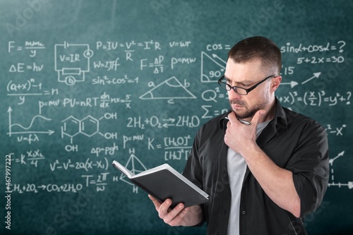 Young teacher man teaching holding book training the mathematics in classroom blackboard