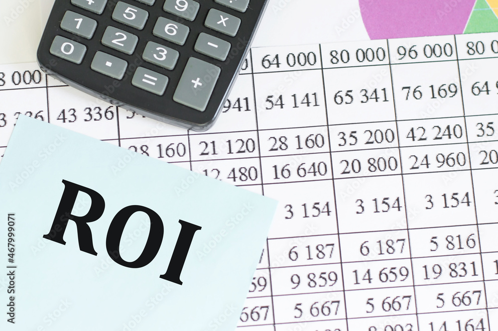 text ROI on a card on an office table among documents, business concept text ROI on a card on an office table among documents, business concept