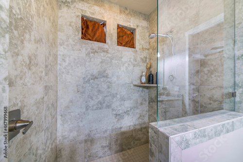Shower stall with gray marble tiles and glass wall panel